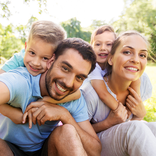 Smiling young family, a mother and father with their toddler boys, outside in the summer.