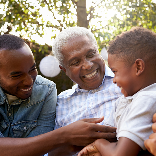 Smiling grandfather, father and toddler at family summer picnic.